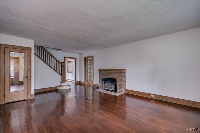 unfurnished living room featuring dark hardwood / wood-style flooring, a brick fireplace, and a textured ceiling