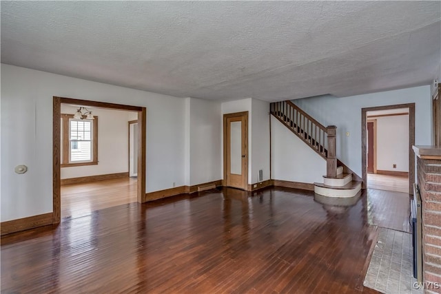 spare room with dark wood-type flooring, a fireplace, and a textured ceiling