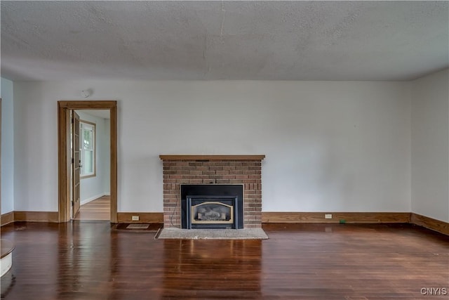 unfurnished living room featuring a fireplace, dark hardwood / wood-style floors, and a textured ceiling