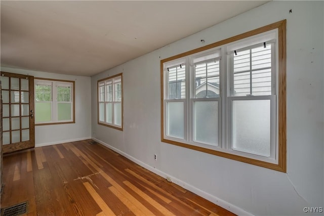 spare room with hardwood / wood-style flooring and plenty of natural light