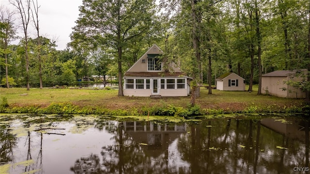 back of property featuring a water view, an outbuilding, and a yard