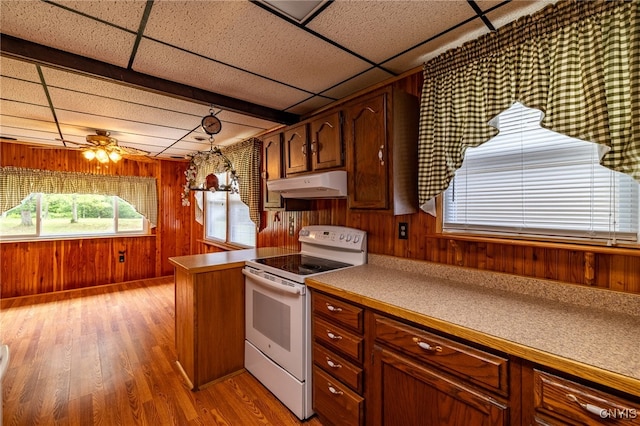 kitchen with electric range, wooden walls, ceiling fan, light hardwood / wood-style floors, and a paneled ceiling