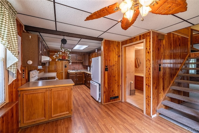 kitchen with range, white refrigerator, wall chimney range hood, light wood-type flooring, and a drop ceiling