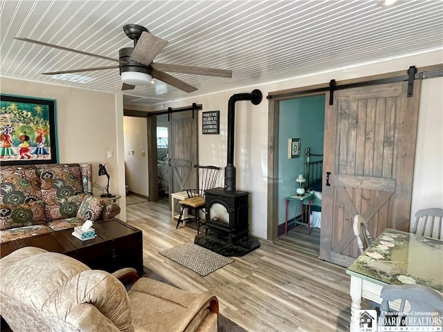 living room with light wood-type flooring, ceiling fan, and a barn door