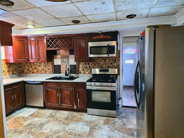 kitchen with sink, ornamental molding, appliances with stainless steel finishes, decorative backsplash, and a drop ceiling