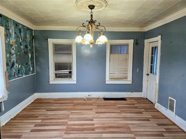 unfurnished dining area featuring an inviting chandelier, crown molding, and light hardwood / wood-style floors