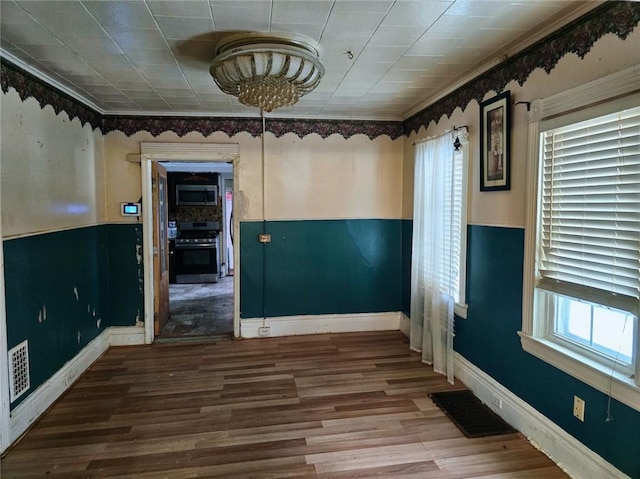 empty room featuring crown molding, wood-type flooring, and a healthy amount of sunlight