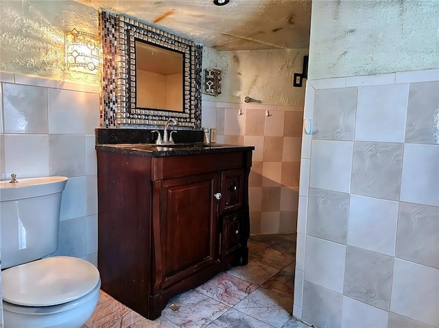 bathroom featuring tile walls, vanity, and toilet