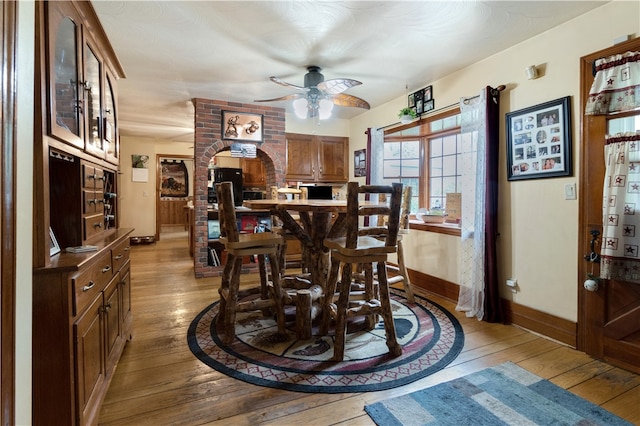 dining space with light hardwood / wood-style flooring, brick wall, and ceiling fan