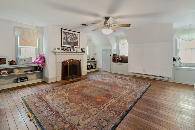 living room with baseboard heating, ceiling fan, vaulted ceiling, and hardwood / wood-style flooring