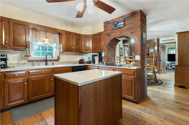 kitchen with light hardwood / wood-style flooring, brick wall, a kitchen island, and ceiling fan