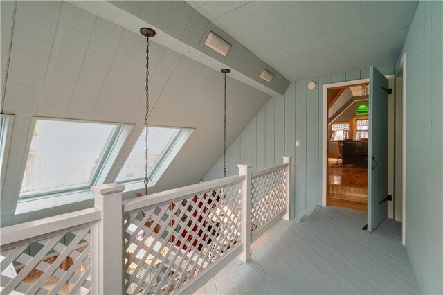 corridor featuring vaulted ceiling with skylight and hardwood / wood-style flooring