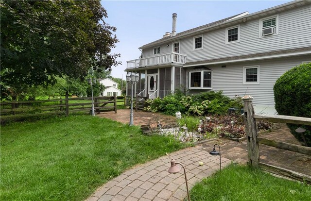 rear view of property featuring a yard and a balcony