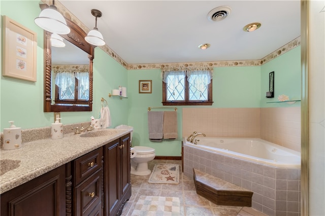 bathroom with tile patterned floors, vanity, a relaxing tiled tub, and toilet