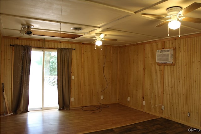 empty room with ceiling fan, a wall unit AC, and wood-type flooring