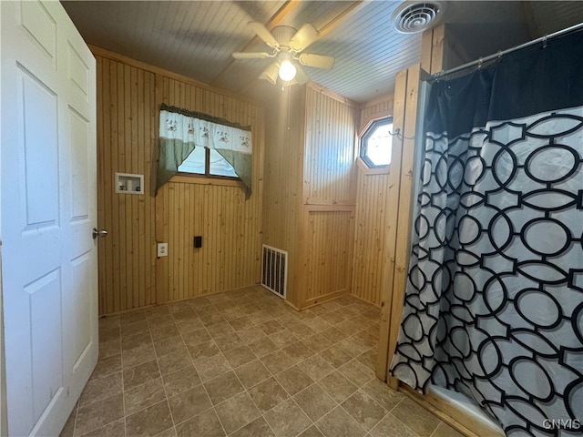 interior space with wood walls and ceiling fan