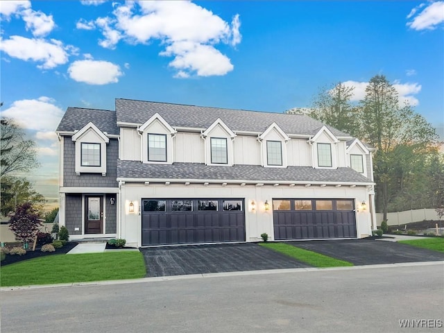 modern inspired farmhouse featuring driveway, an attached garage, fence, and roof with shingles