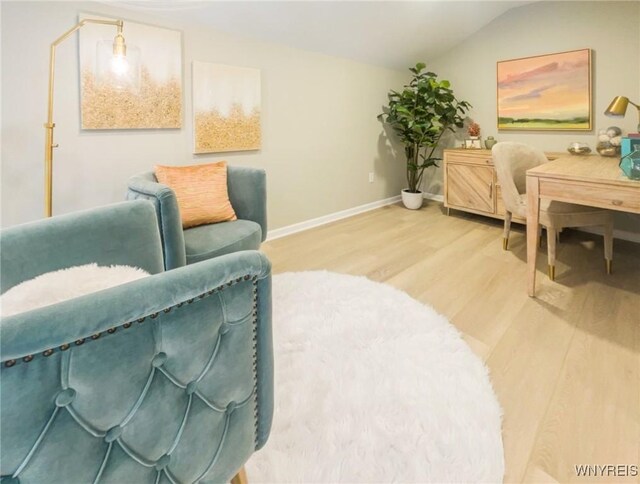 living area with lofted ceiling, wood finished floors, and baseboards