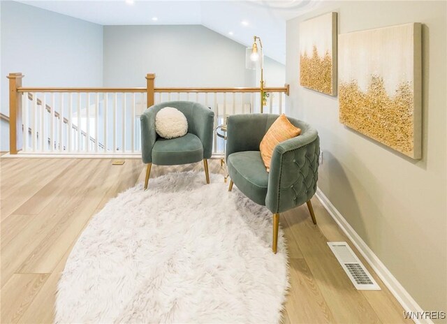 sitting room with vaulted ceiling, wood finished floors, visible vents, and baseboards