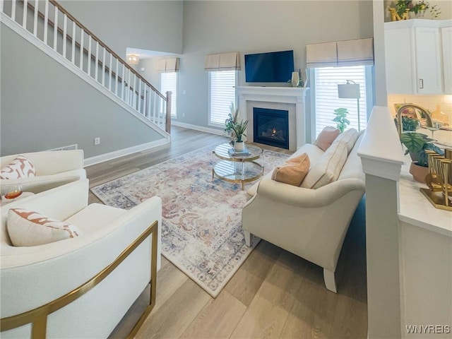 living area featuring light wood-style floors, plenty of natural light, and a glass covered fireplace