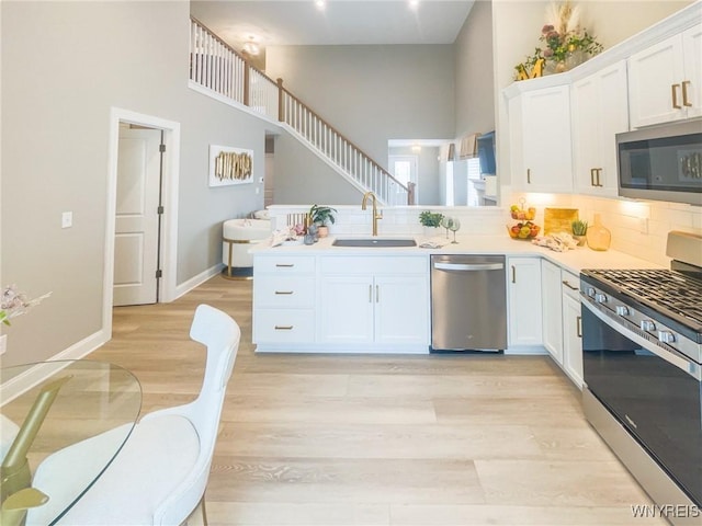 kitchen with white cabinetry, stainless steel appliances, kitchen peninsula, and sink