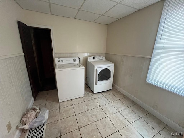 clothes washing area featuring light tile patterned floors, laundry area, wainscoting, and washer and dryer