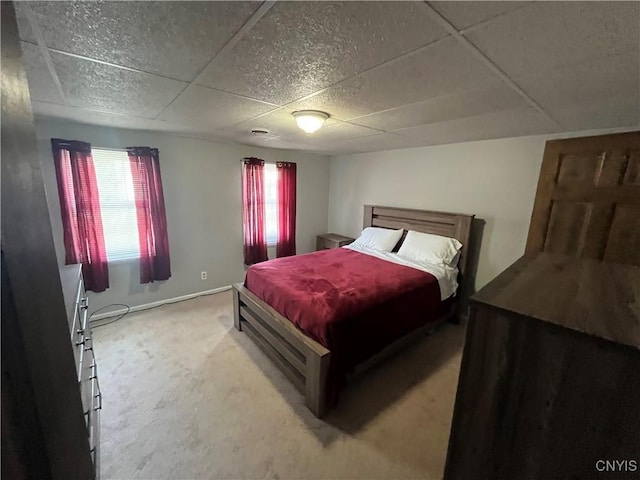 carpeted bedroom with a drop ceiling and baseboards