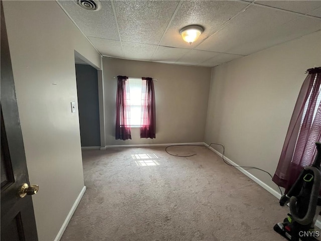 spare room with carpet floors, a paneled ceiling, visible vents, and baseboards