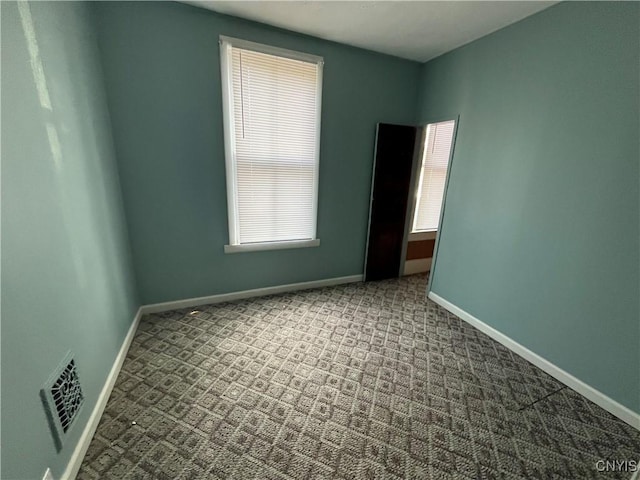 empty room featuring carpet floors, baseboards, and visible vents