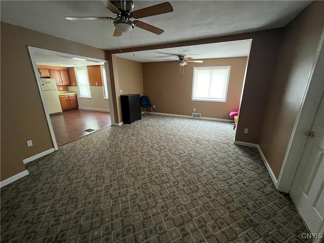 empty room featuring visible vents, baseboards, and dark carpet