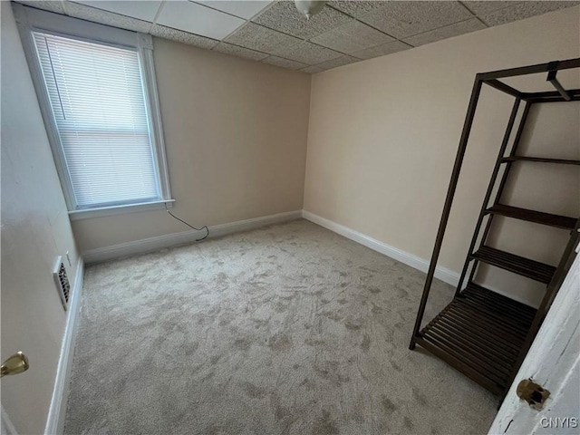 unfurnished bedroom with a paneled ceiling, light carpet, visible vents, and baseboards