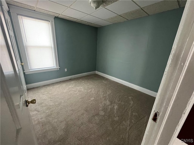 carpeted empty room with a paneled ceiling and baseboards