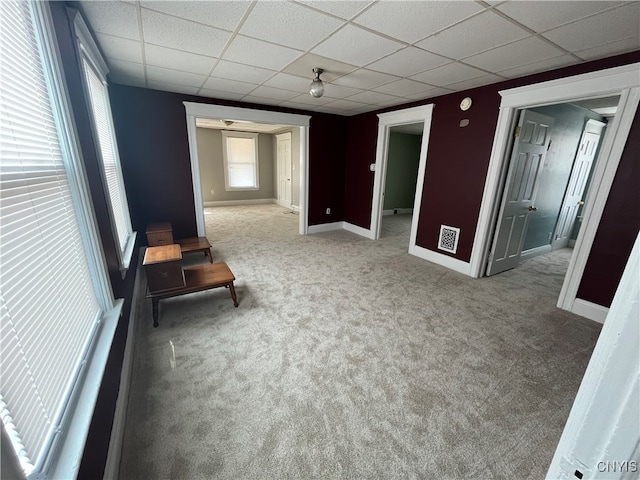 carpeted empty room with a drop ceiling