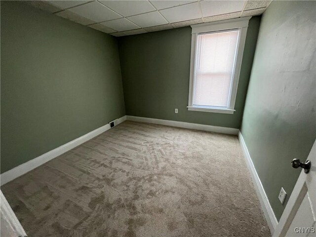 carpeted empty room with a drop ceiling