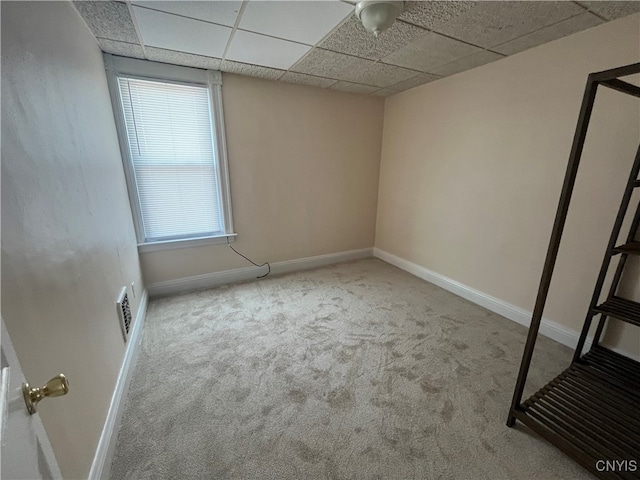 spare room with a paneled ceiling and light colored carpet