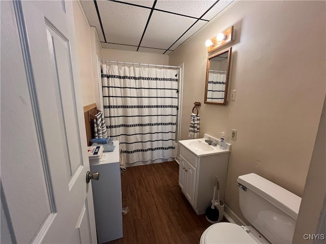 full bathroom with a paneled ceiling, curtained shower, toilet, vanity, and wood finished floors