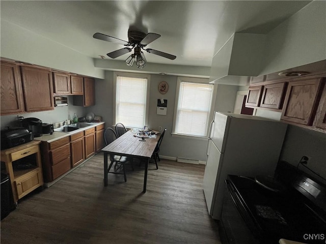 kitchen featuring baseboards, brown cabinetry, dark wood-style flooring, light countertops, and a sink