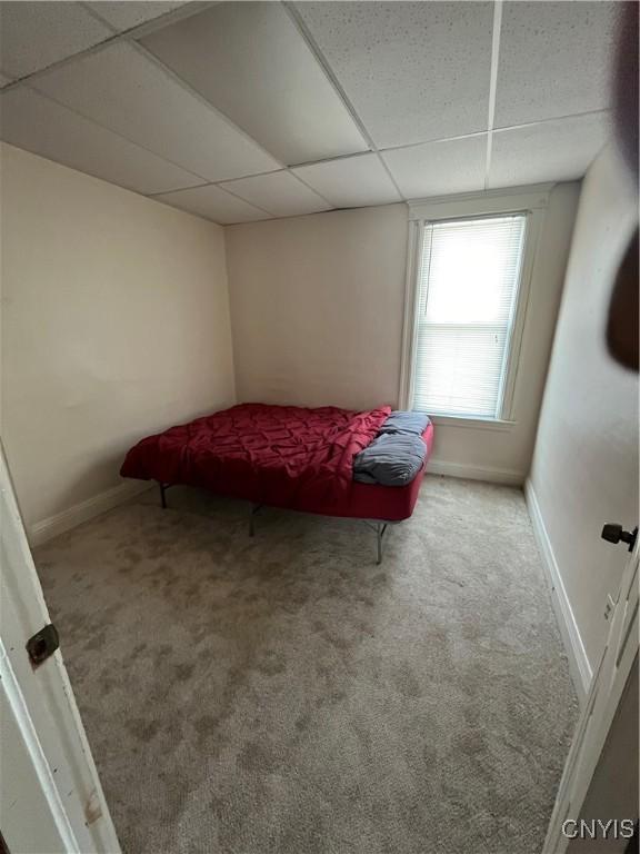 carpeted bedroom featuring a drop ceiling