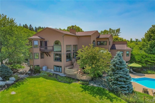 back of property featuring a lawn, central AC unit, and a balcony