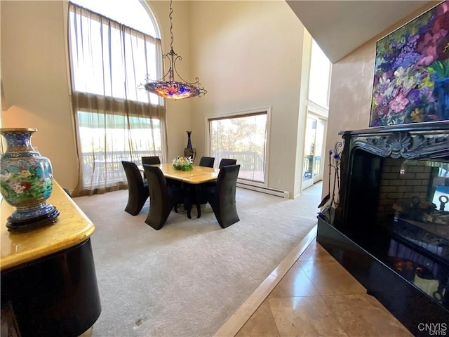 dining room with a towering ceiling, carpet, and a baseboard radiator