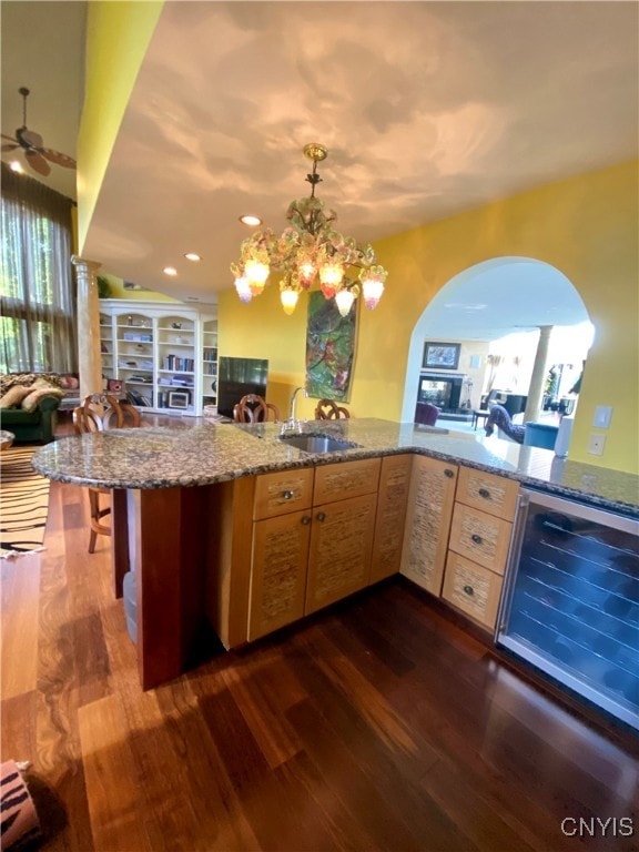 kitchen featuring beverage cooler, kitchen peninsula, sink, and dark wood-type flooring