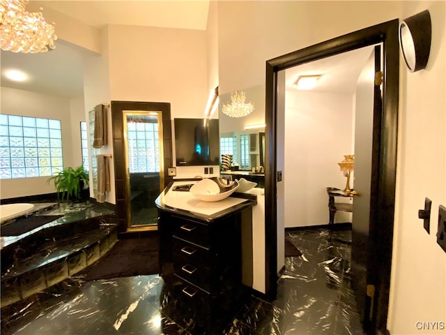 bathroom with a chandelier, vanity, a tub, and a healthy amount of sunlight