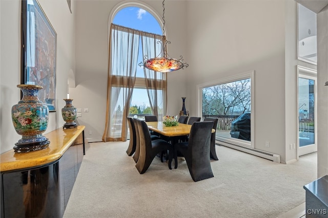 dining area with baseboard heating, carpet, and a high ceiling