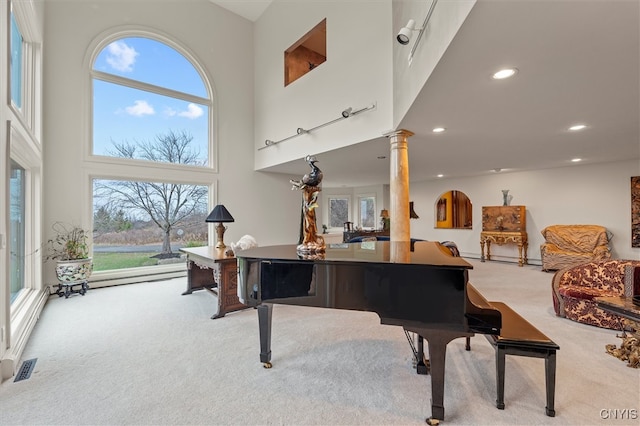 misc room featuring a high ceiling, plenty of natural light, light carpet, and decorative columns