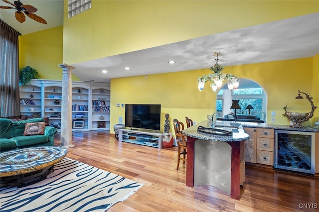 living room with sink, wine cooler, hardwood / wood-style floors, lofted ceiling, and ceiling fan with notable chandelier