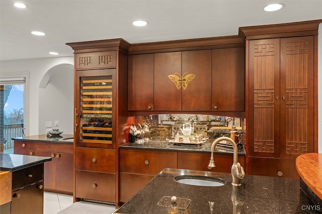 bar with sink, light tile patterned flooring, wine cooler, dark stone countertops, and backsplash