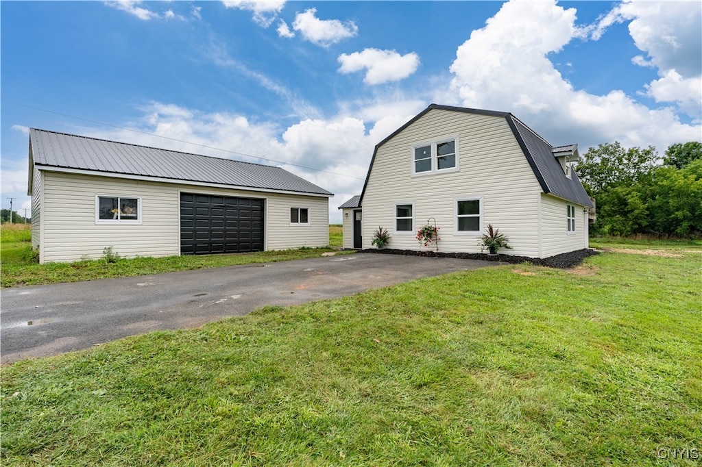 view of home's exterior with a garage, a lawn, and an outdoor structure