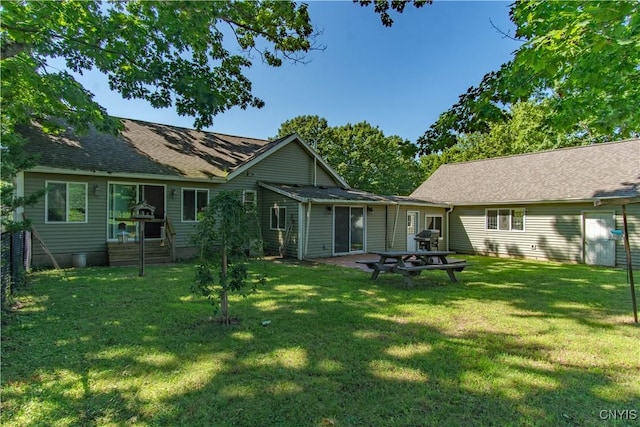 rear view of house featuring an outdoor fire pit and a lawn