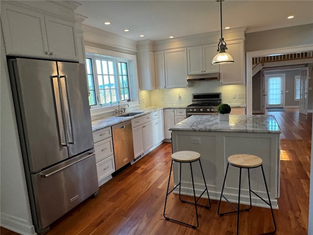 kitchen featuring high quality appliances, backsplash, white cabinetry, and hardwood / wood-style floors