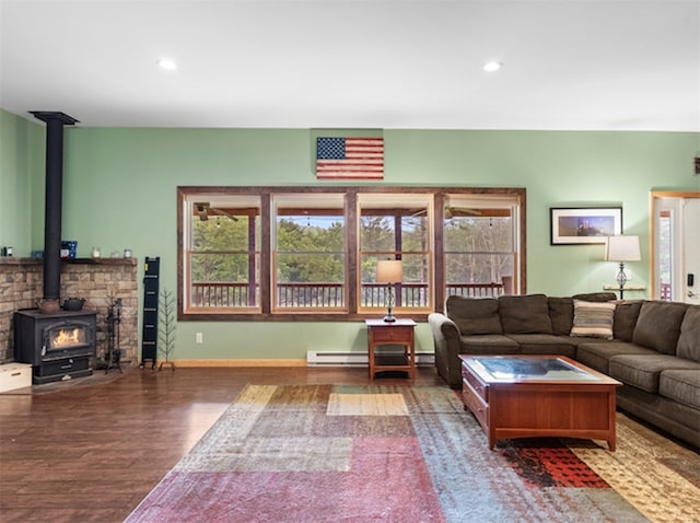 living room featuring baseboard heating, hardwood / wood-style flooring, and a wood stove